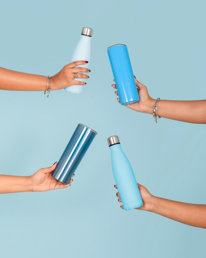 Verschillende mensen houden elk een eigen gekleurde herbruikbare drinkfles vast tegen een lichtblauwe achtergrond
