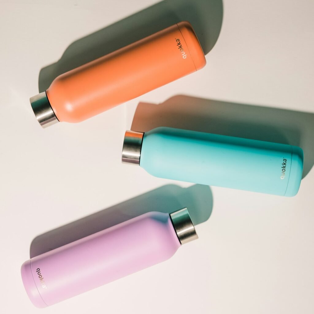 Drie gekleurde RVS drinkflessen naast elkaar, elk met een ander formaat en kleur, als voorbeeld van materiaalkeuze bij het kopen van een drinkfles
